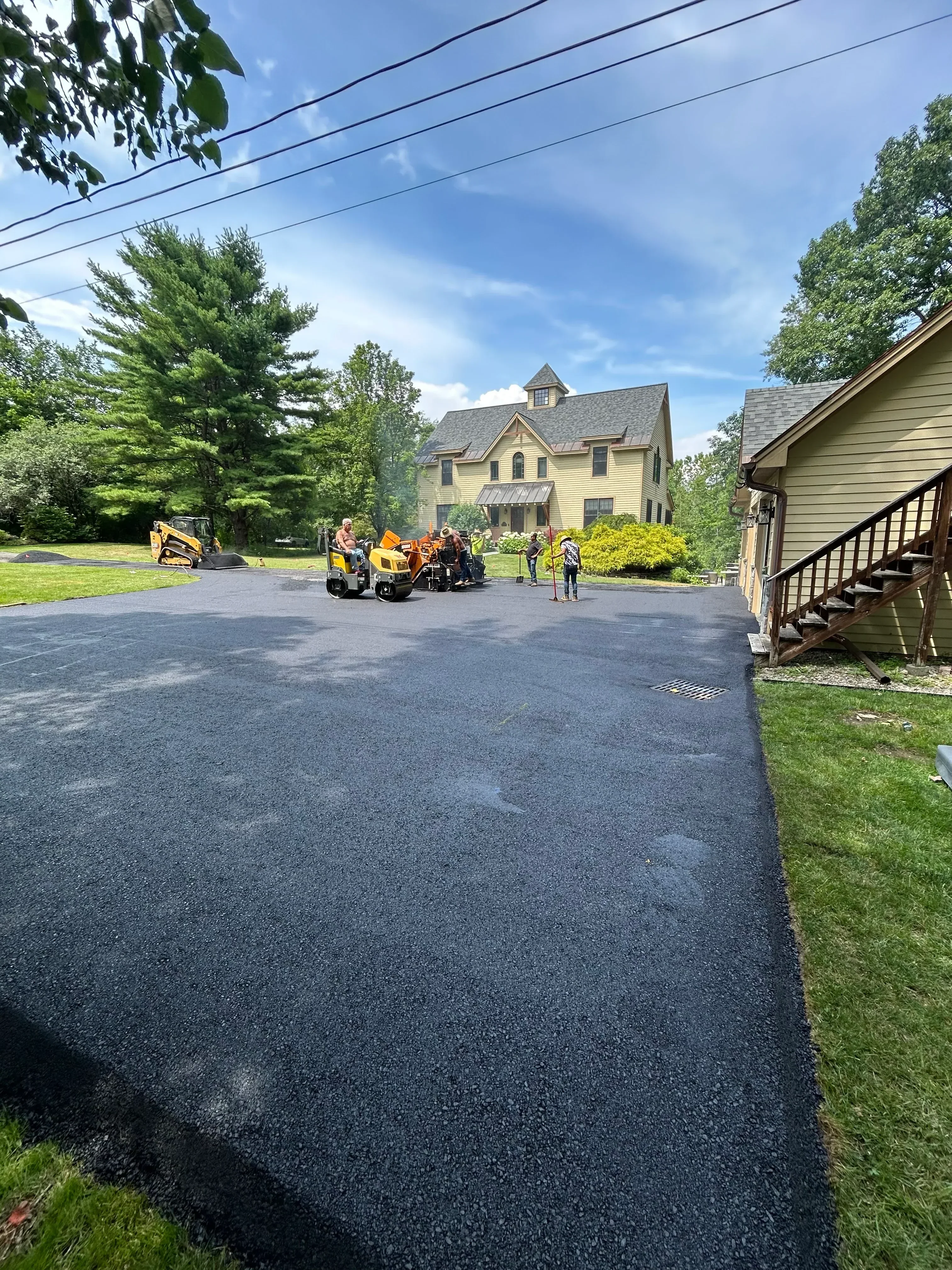 Newly installed dark asphalt driveway with compacted surface and proper grading
