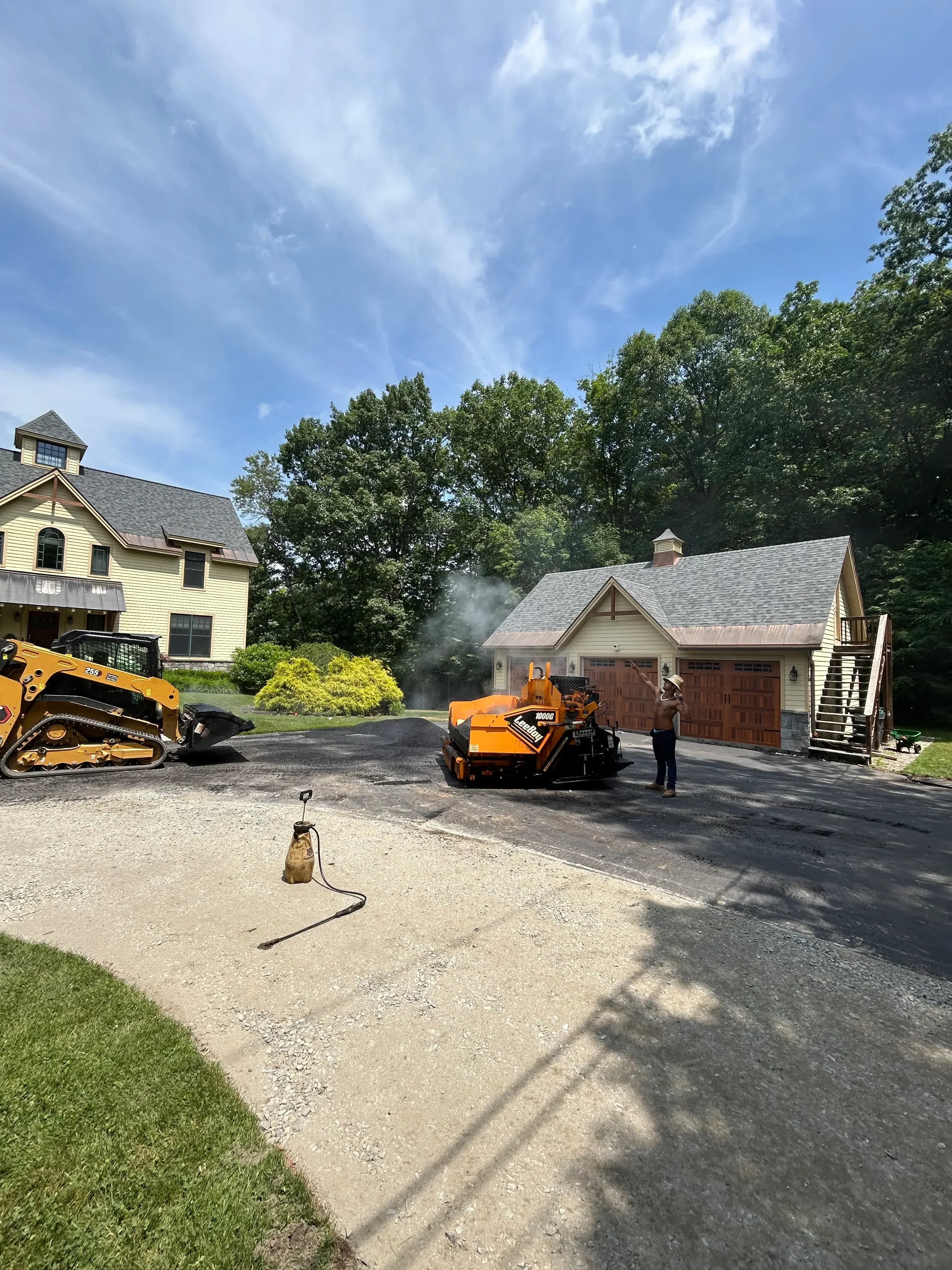 Asphalt paving equipment compacting fresh asphalt on residential driveway