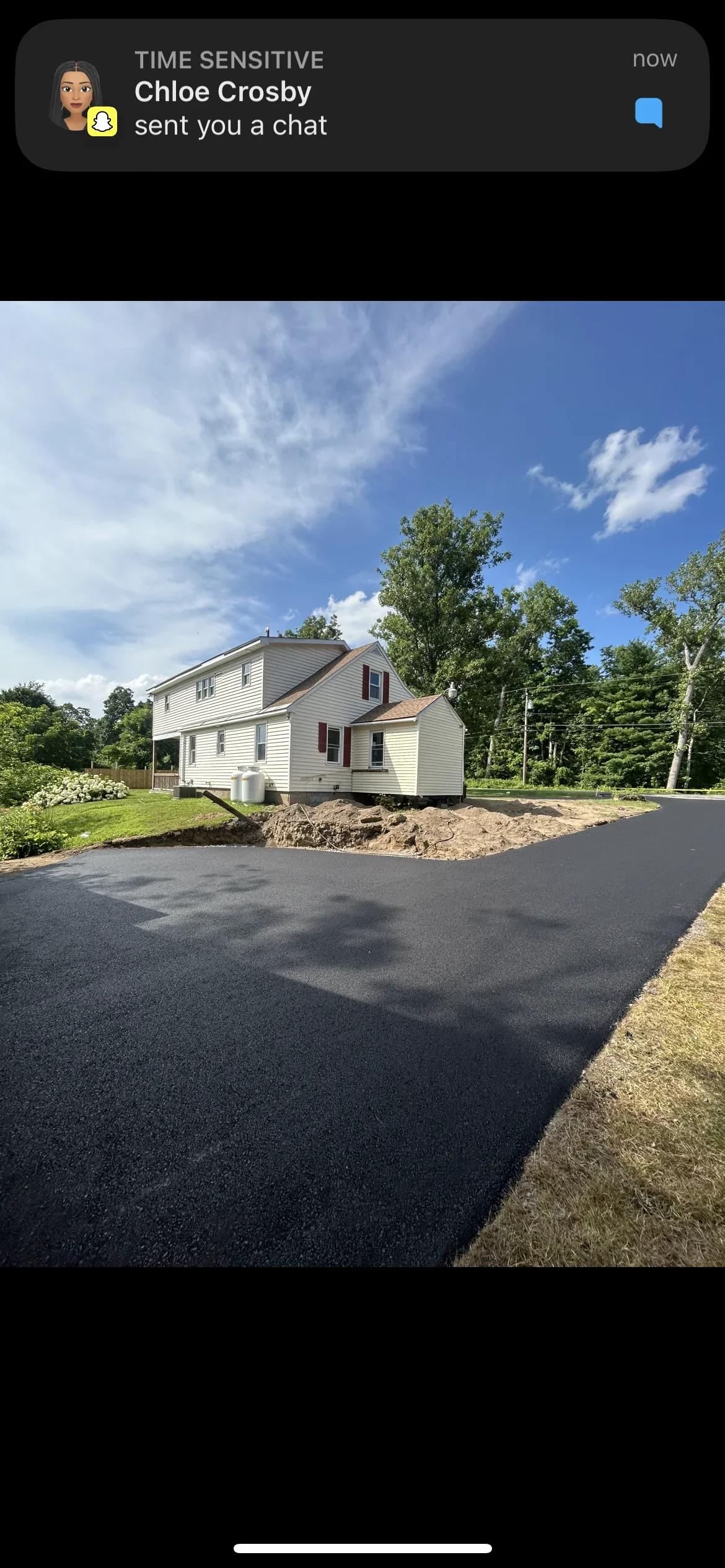 New black asphalt driveway with fresh paving and graded base material at residential home
