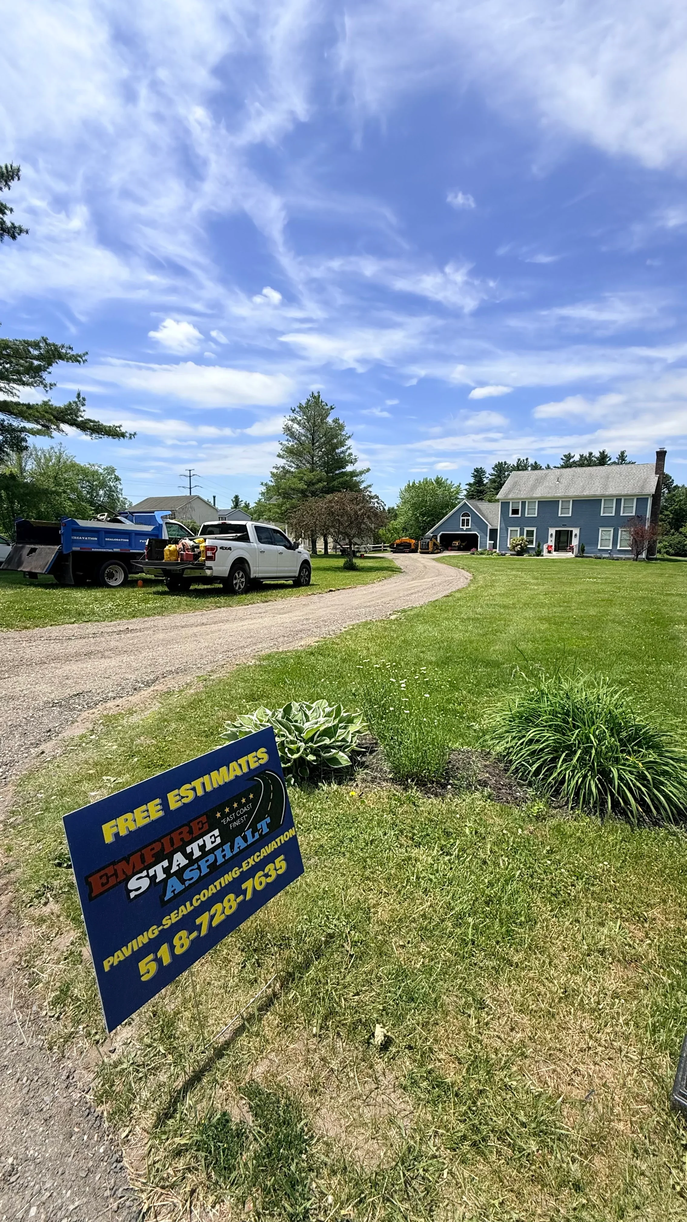 Newly installed curved asphalt driveway leading to residential home with service vehicle on site