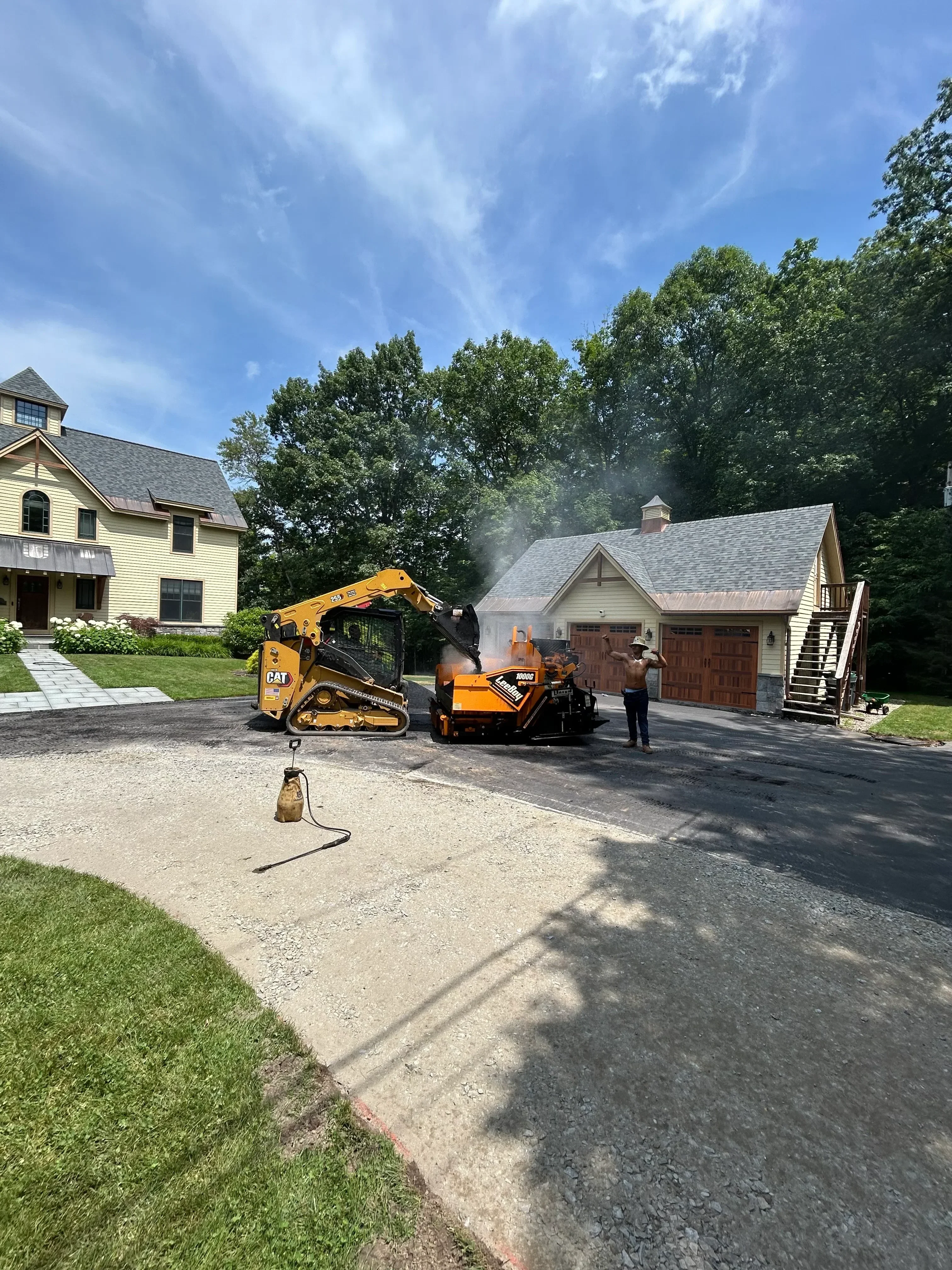Asphalt driveway installation with compaction equipment at residential home