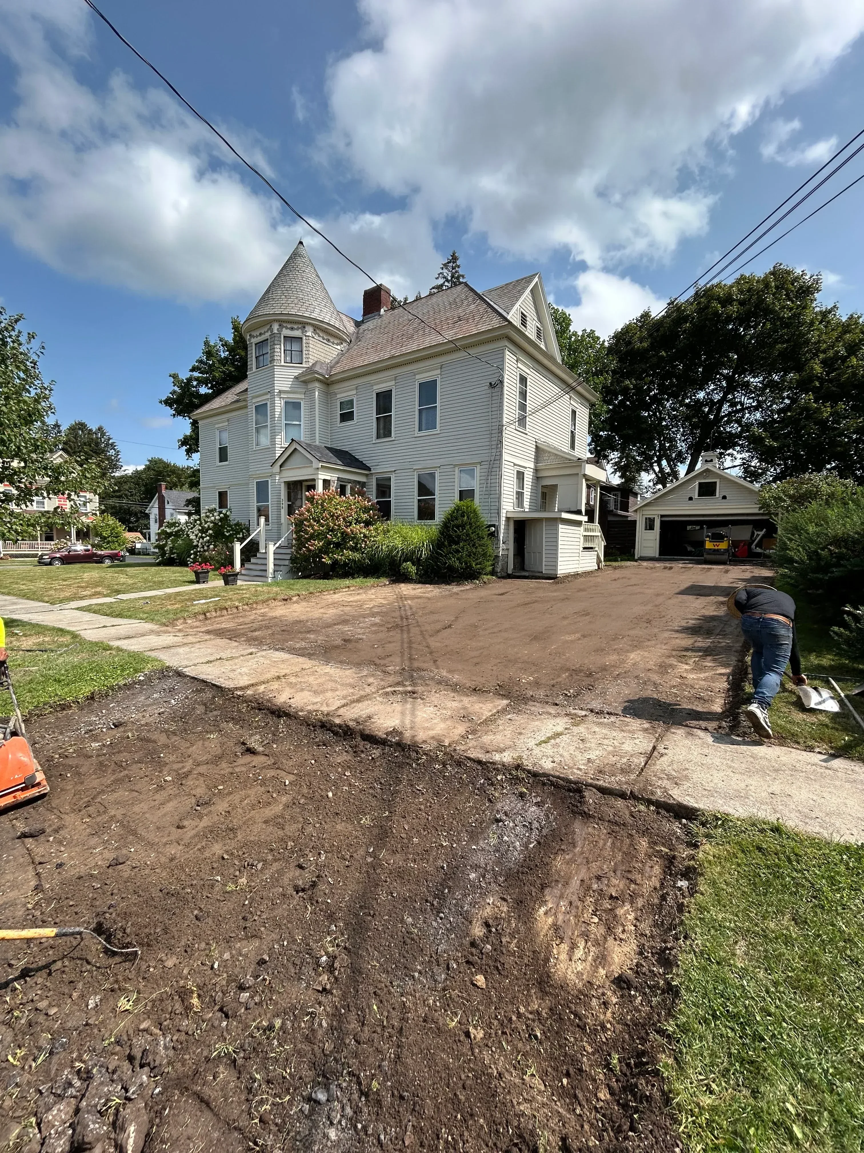 Newly installed asphalt driveway alongside residential home with metal siding