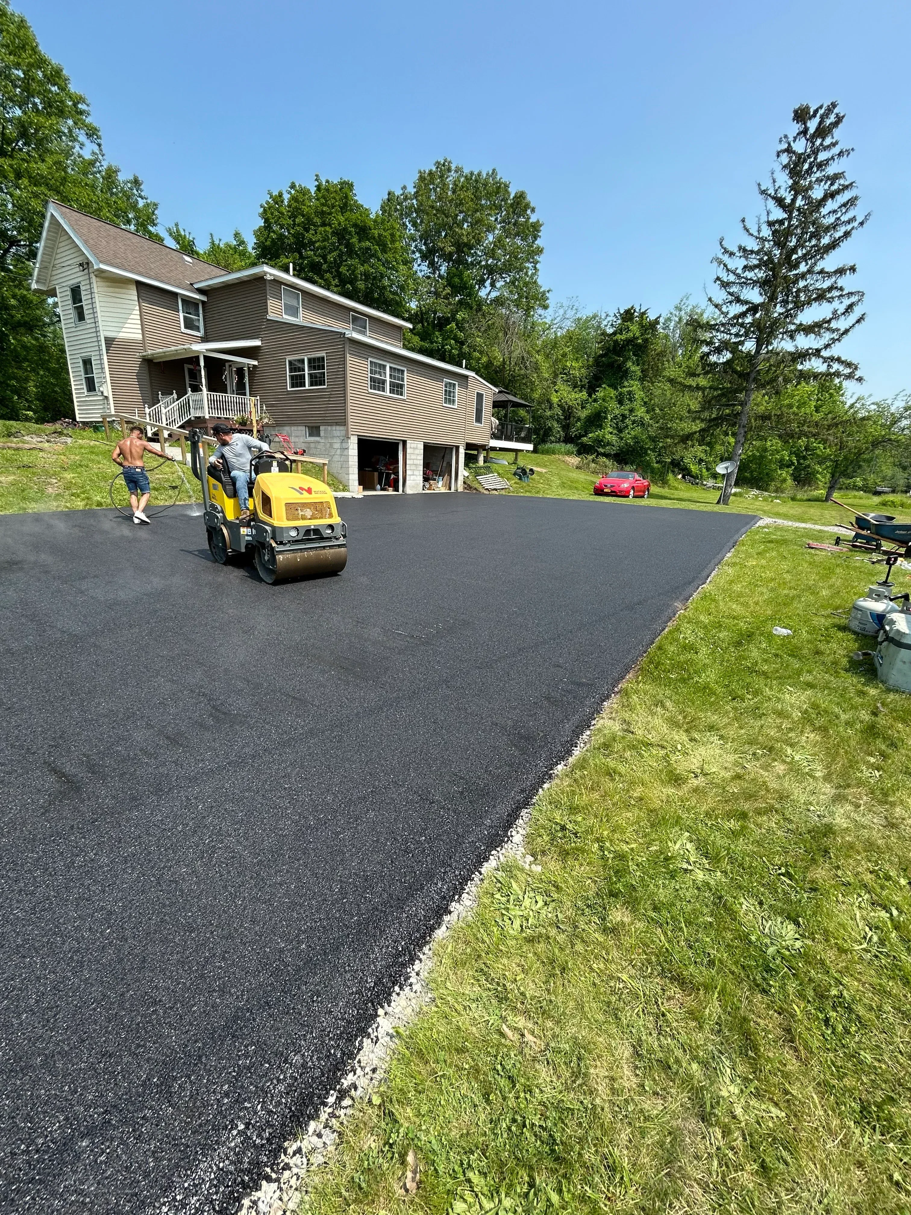 New asphalt driveway with white stone edge next to residential home