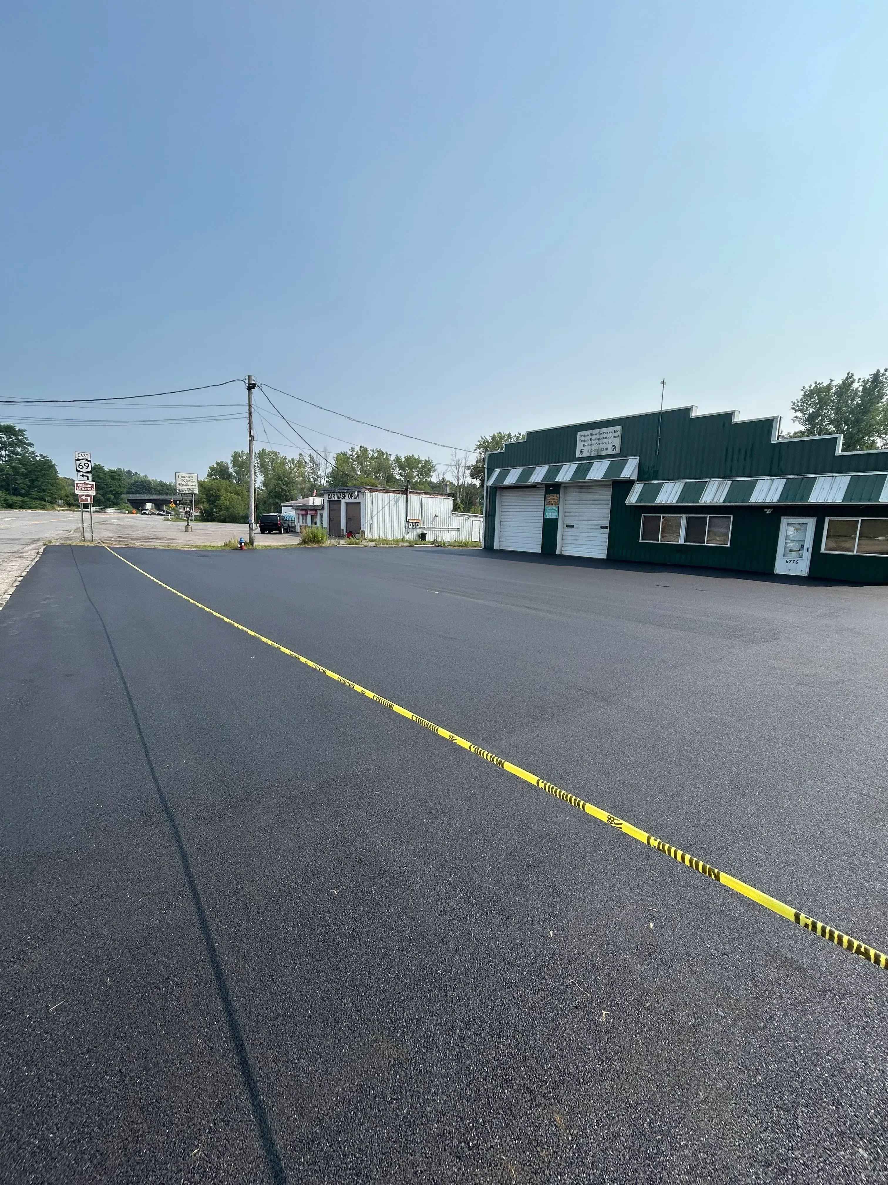 Newly installed dark asphalt driveway with yellow center line marking on residential property