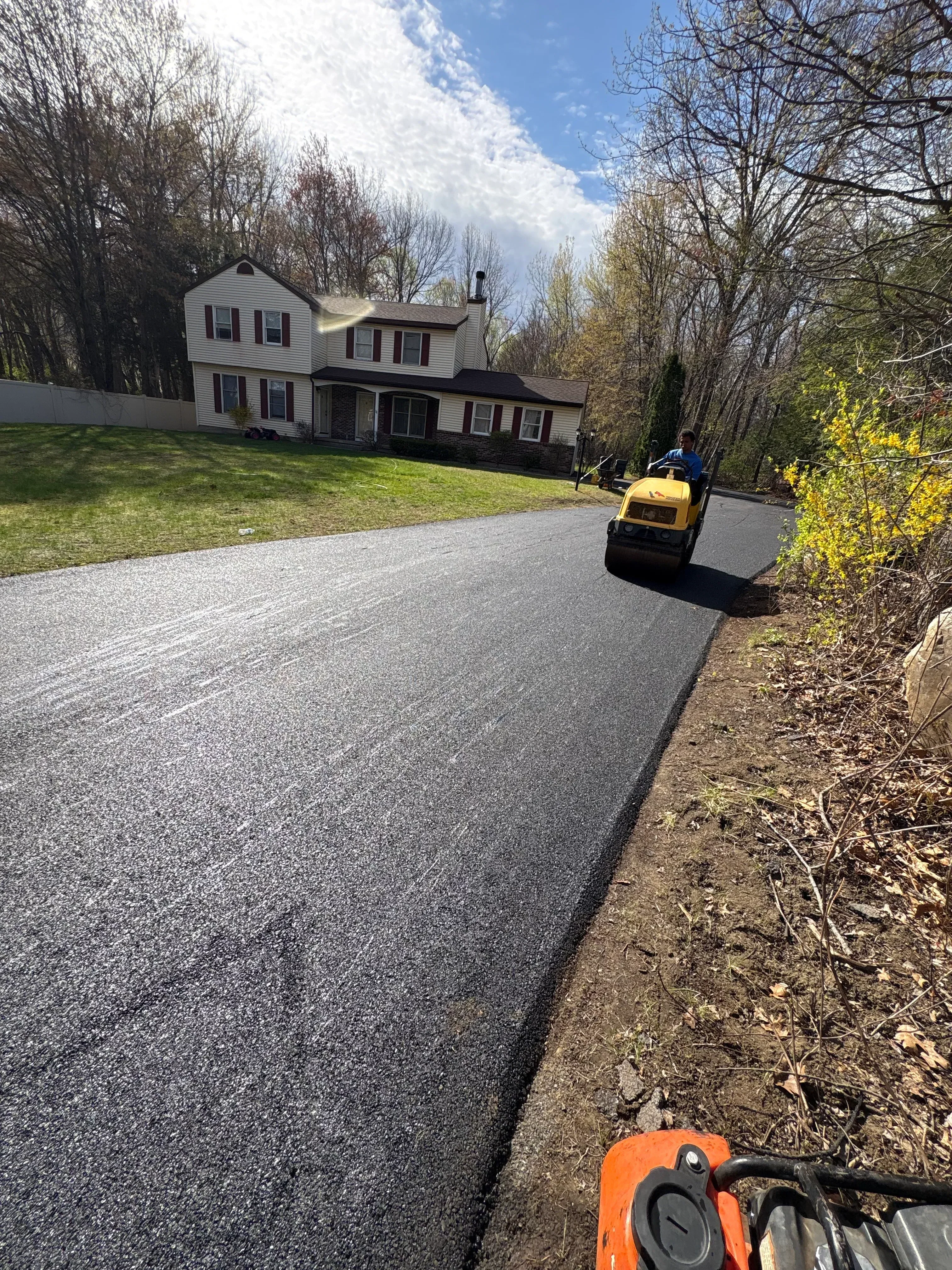 Newly installed dark asphalt driveway with smooth finish and proper grading
