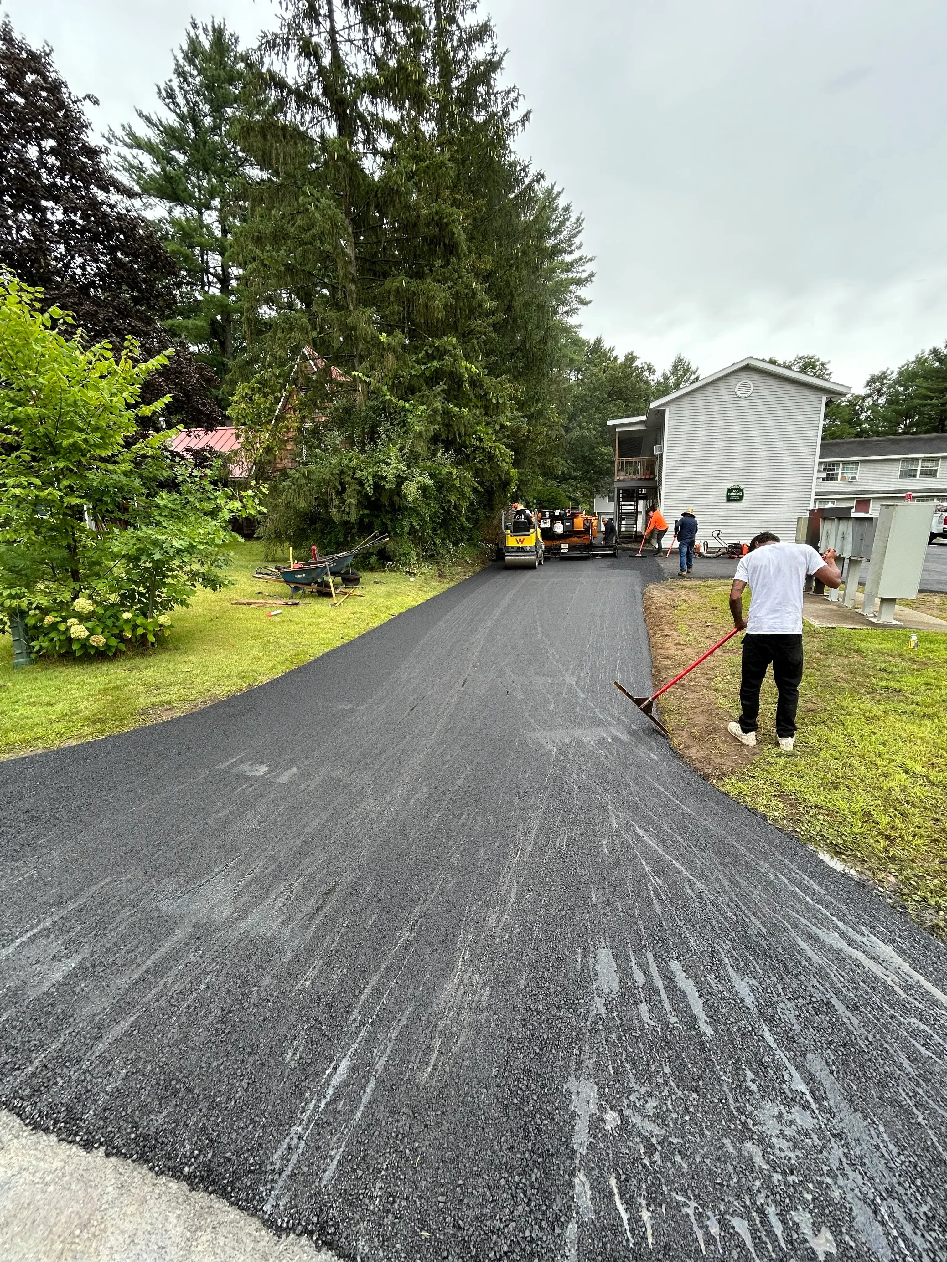 Newly installed dark asphalt driveway with uniform surface finish and proper slope grading
