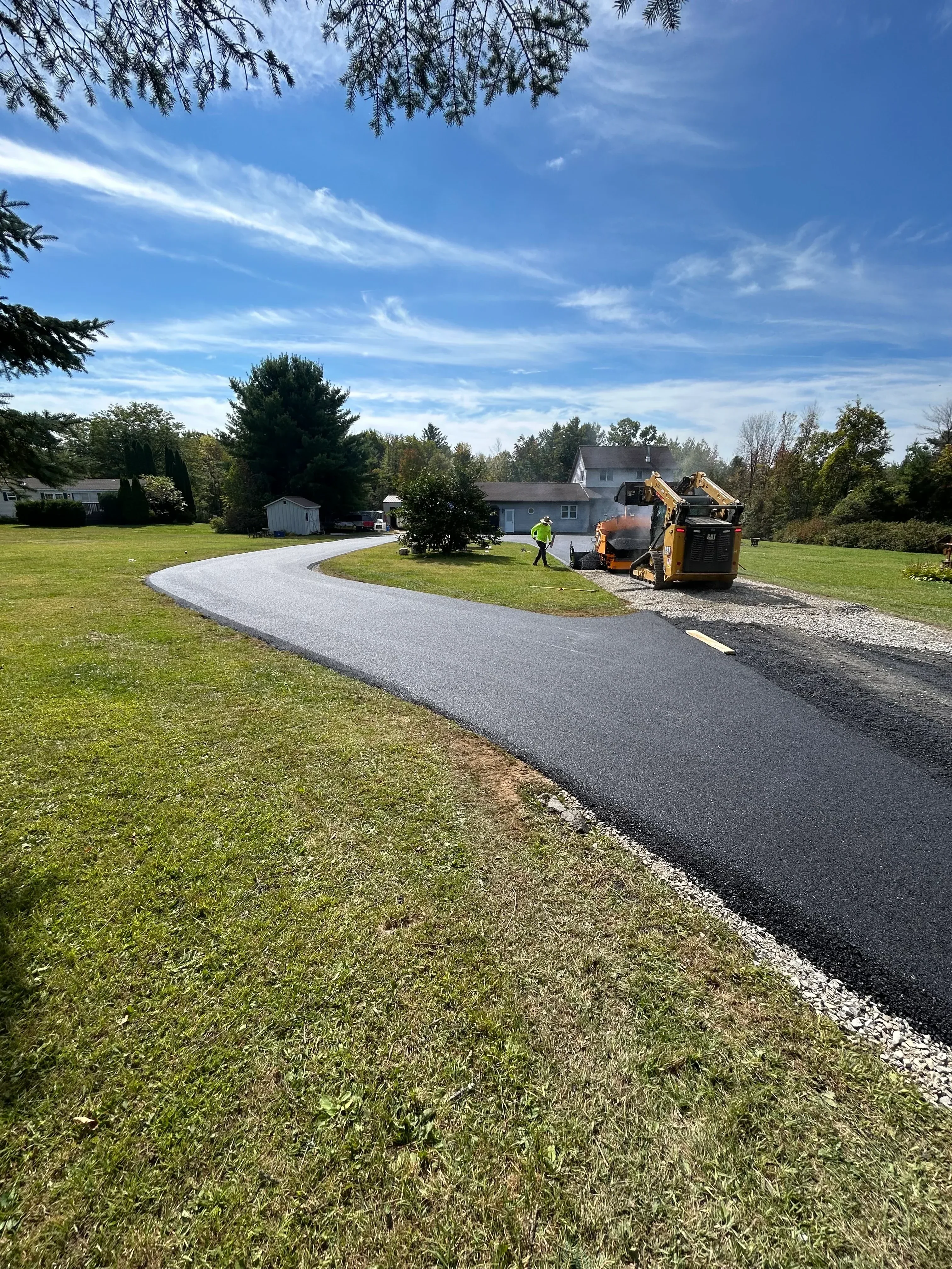Newly installed asphalt driveway with dark pavement and clean edges adjacent to green lawn