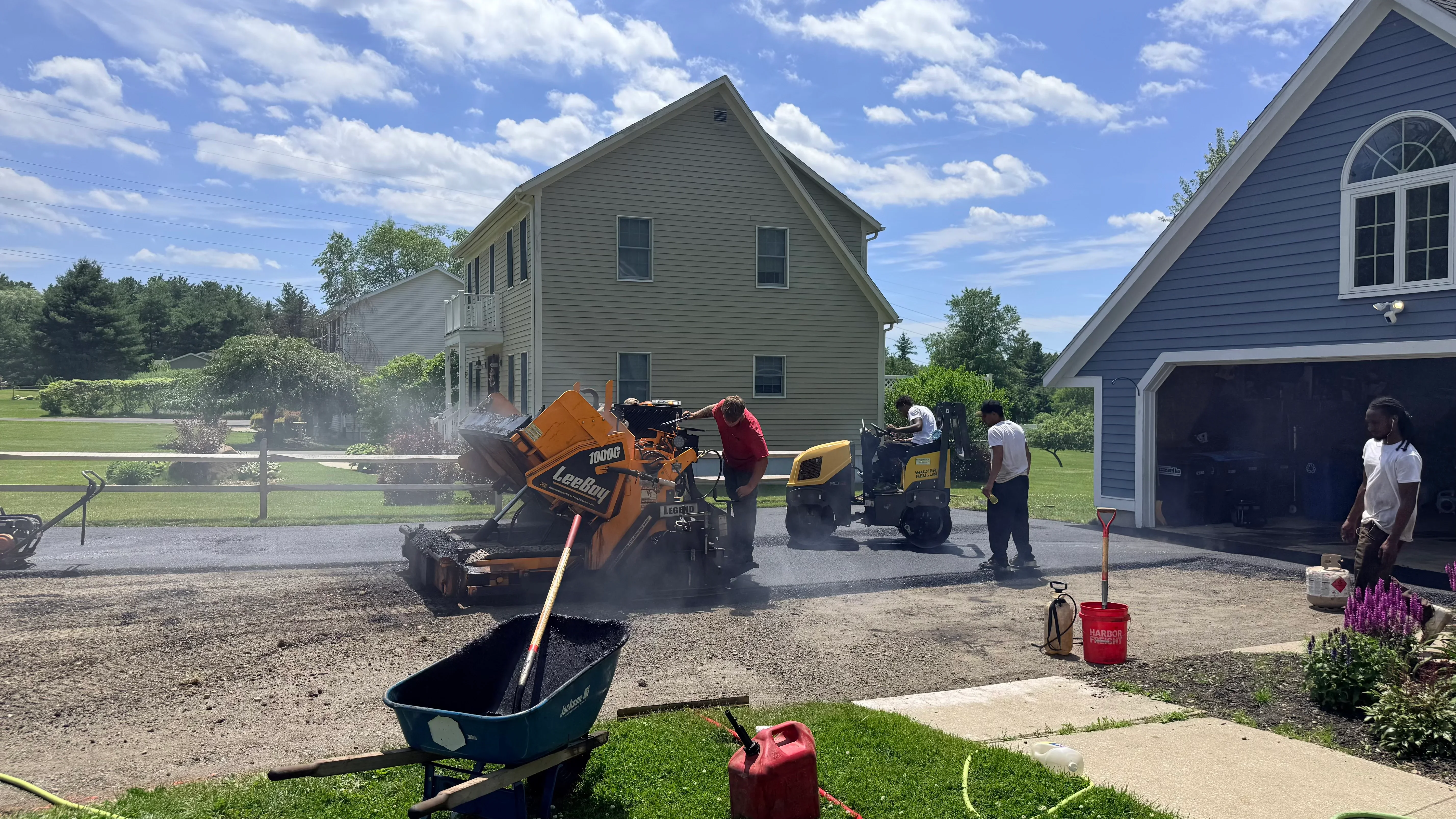 Asphalt milling machine and paving equipment installing new driveway with crew on residential property