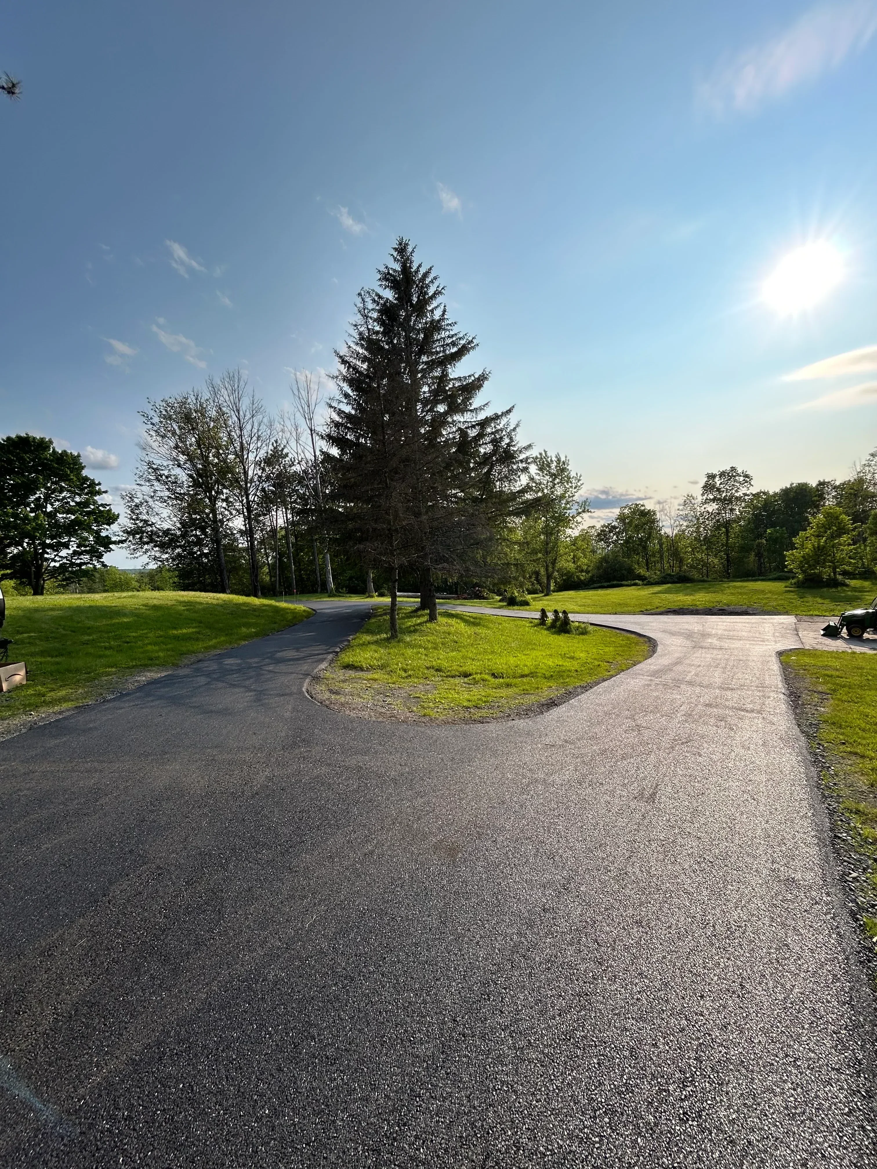 Newly paved asphalt driveway with dark gray surface and manicured lawn edges